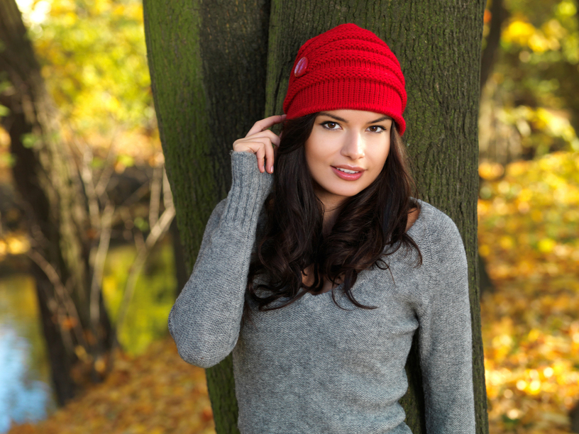 Smiling brunette Beauty during autumn wearing red beannie hat