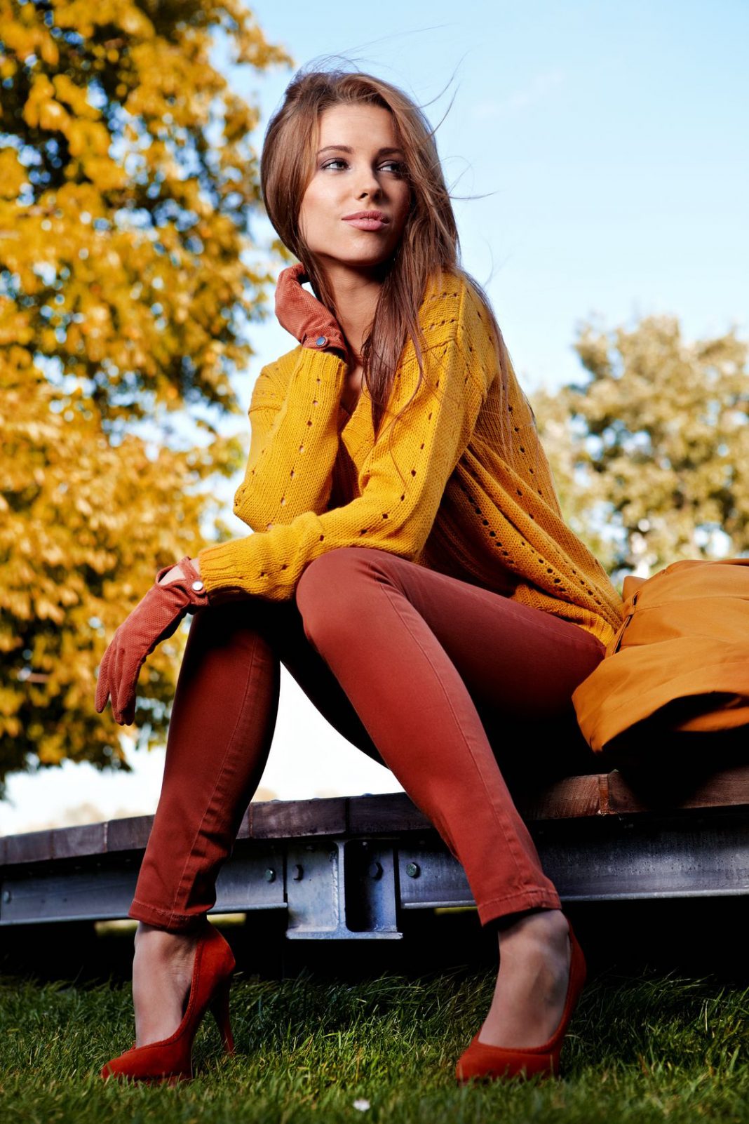 woman wearing mustard yellow sweater and marron red pants posing outdoors in fall autumn