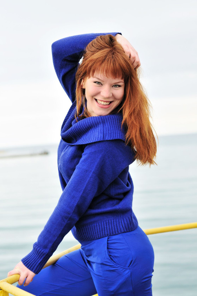 cute red-headed girl wearing bright blue sweater on boat
