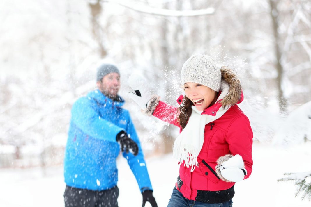 Couple playing snow ball fight in the snow