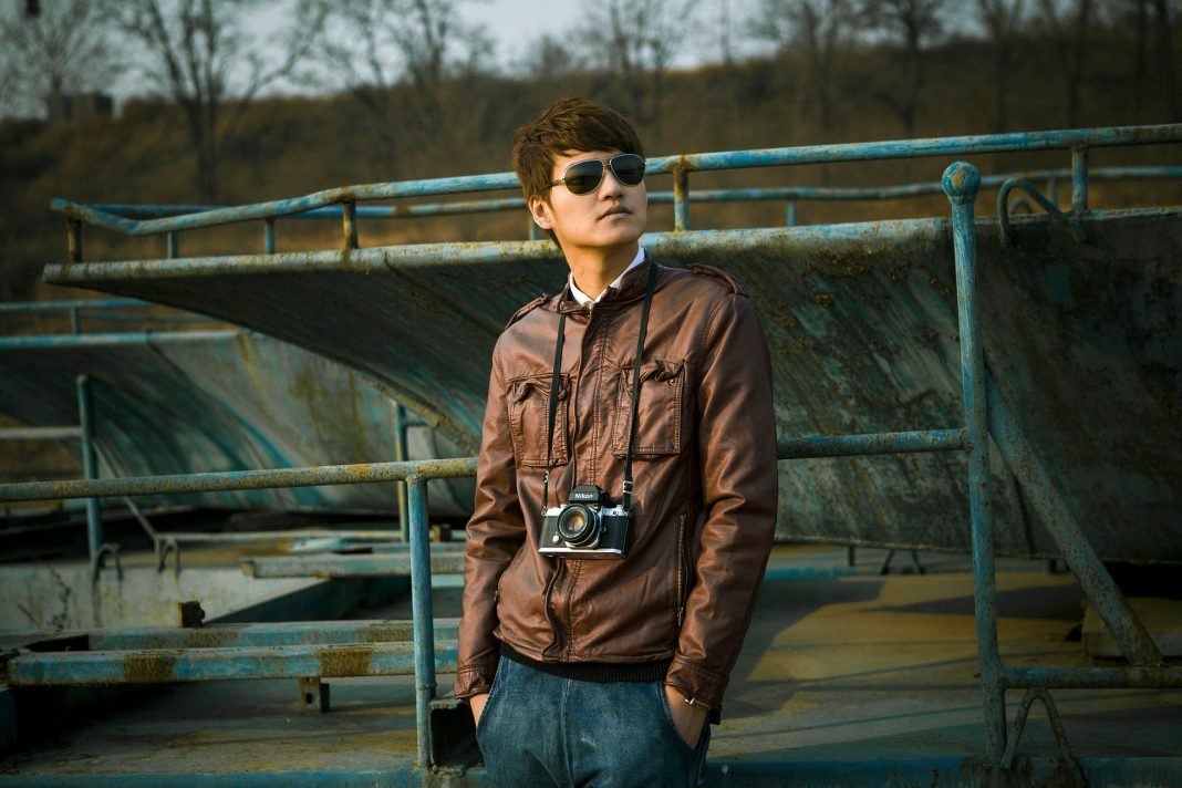 man in sunglasses jeans and brown jacket