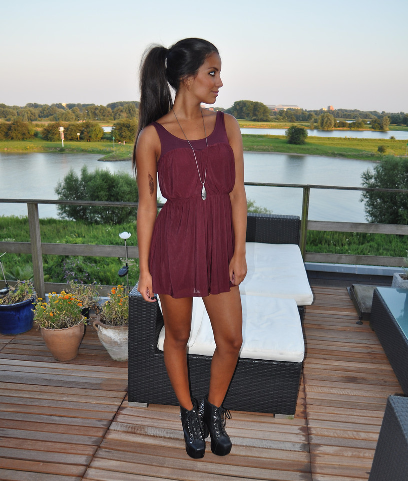 Blogger Stephanie Abu-Sbeih from The Netherlands wears black ankle boots with a burgundy dress
