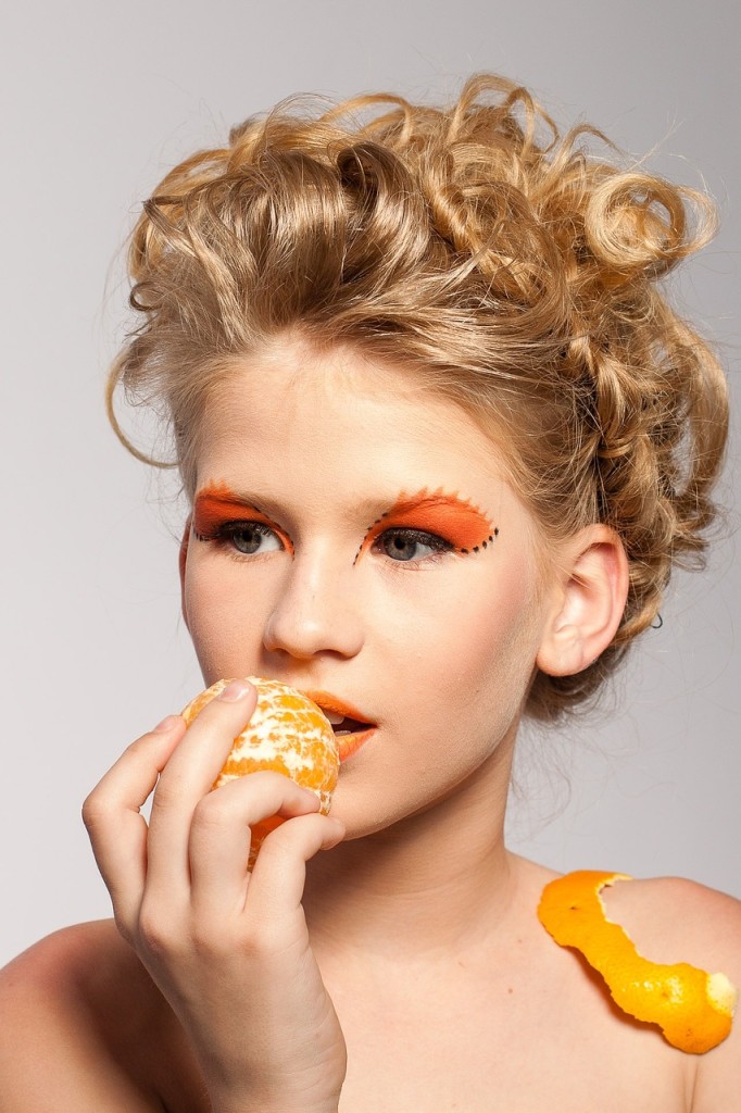 Pretty girl modeling pretend eating tangerine