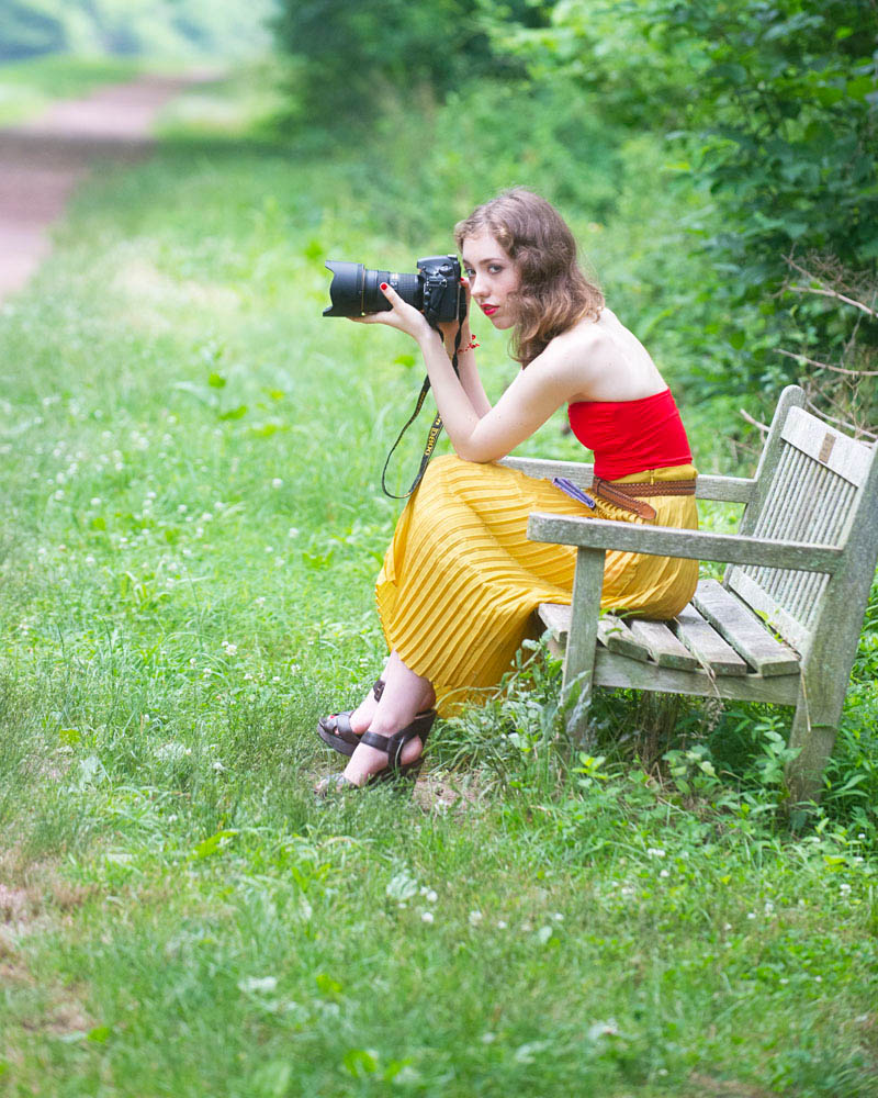 Andrea Charlaine from the blog Andrea Charlaine wearing a red bathing suit top with a yellow pleated maxi skirt