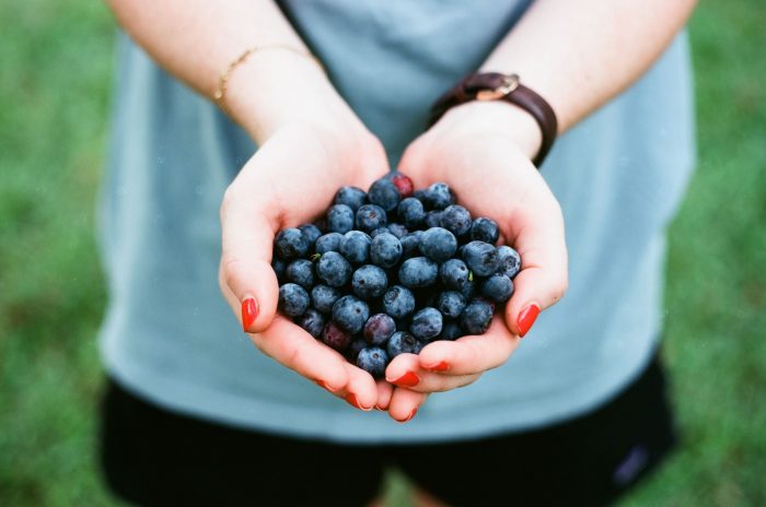 a woman holds a handful of blueberries