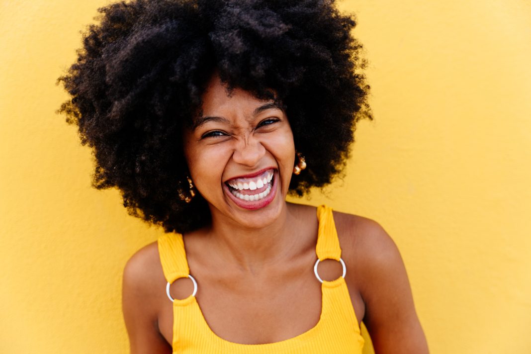 Smiling happy woman against yellow background