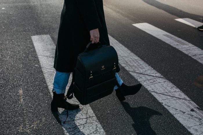 person walking in the street carrying a work bag